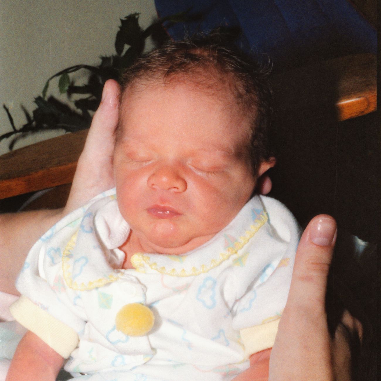 A sleeping newborn cradled gently in hands
