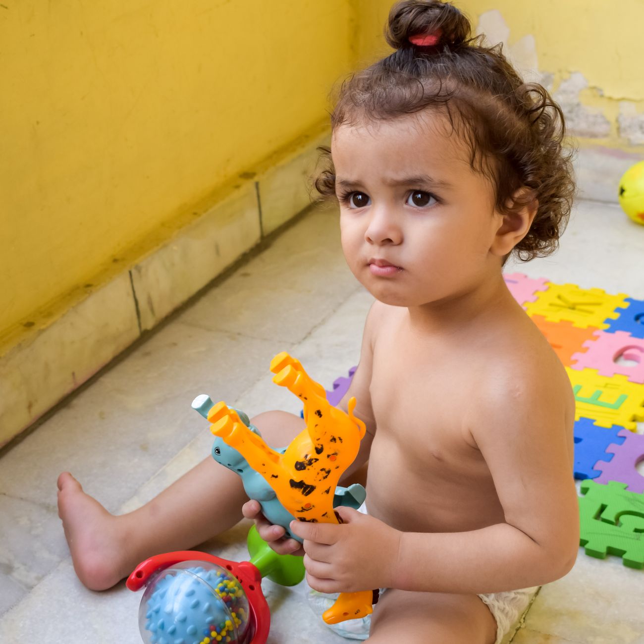 A toddler focused on playing with colourful toys