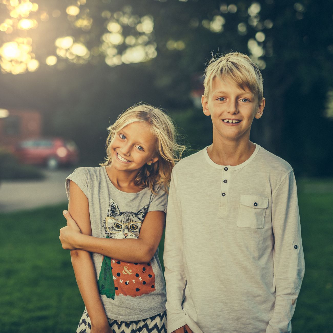A brother and sister smiling in a sunlit garden